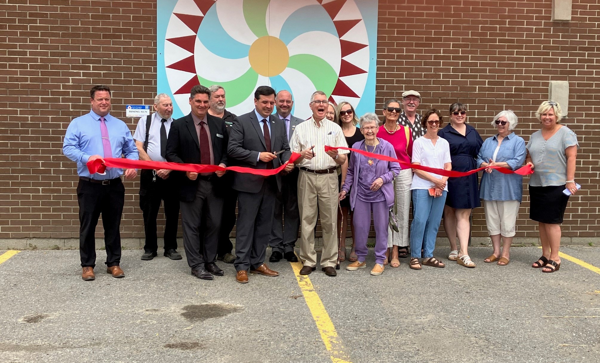 Council and members of the Barn Quilt Committee cutting a ribbon on the barn quilt